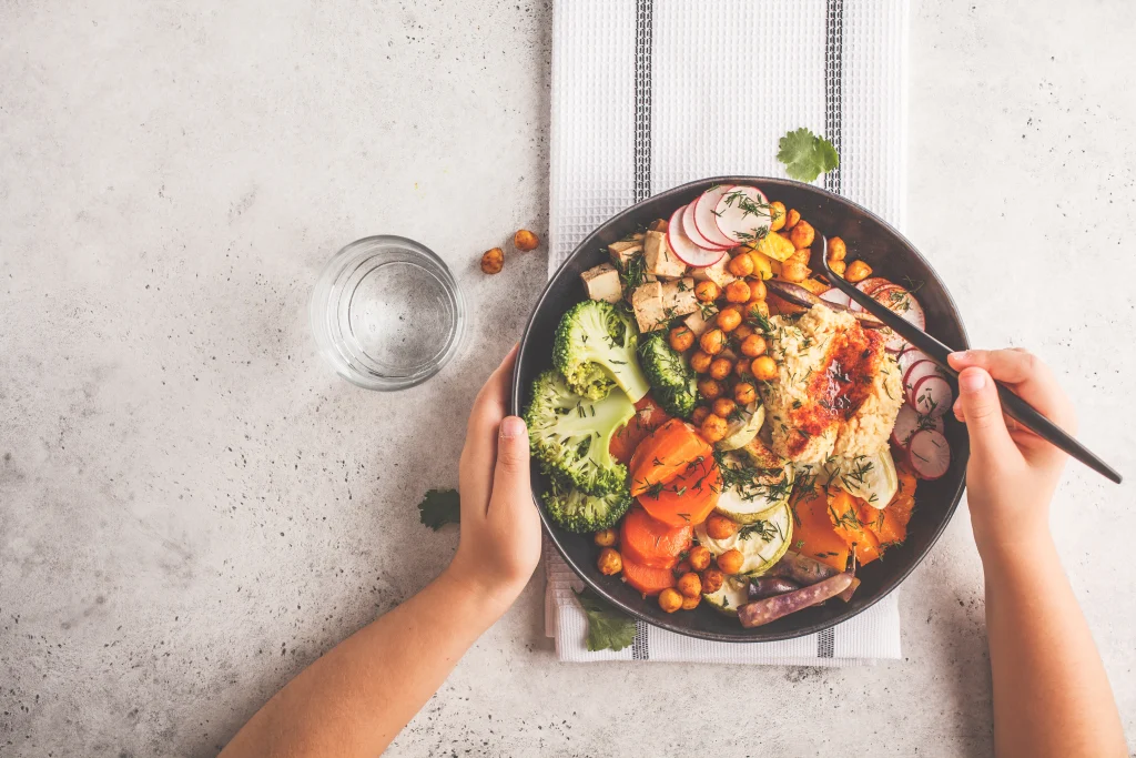 two hands holding a bowl of vegetables