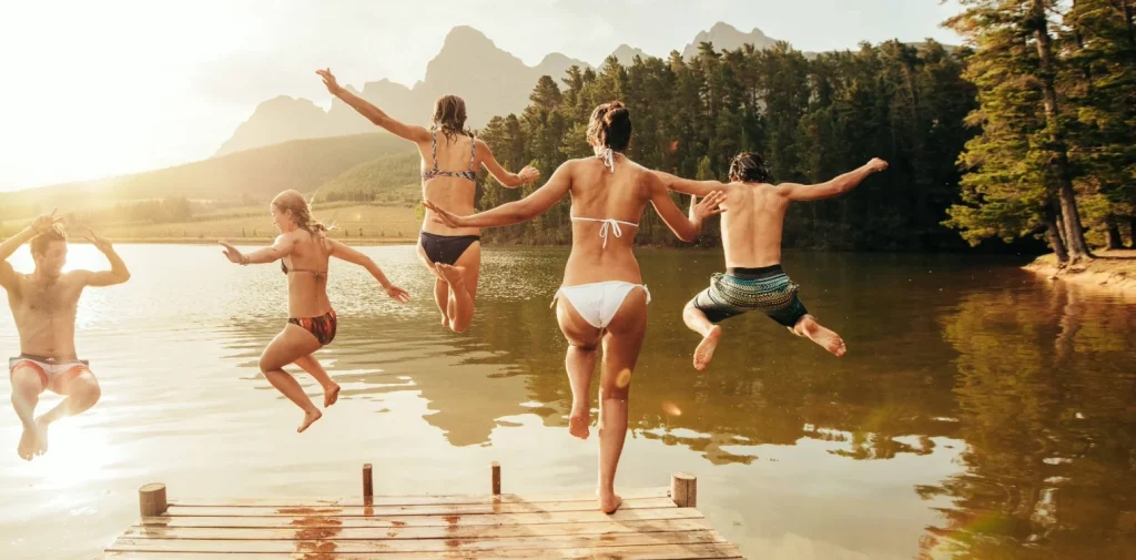 Group of people jumping into a lake in swim suits