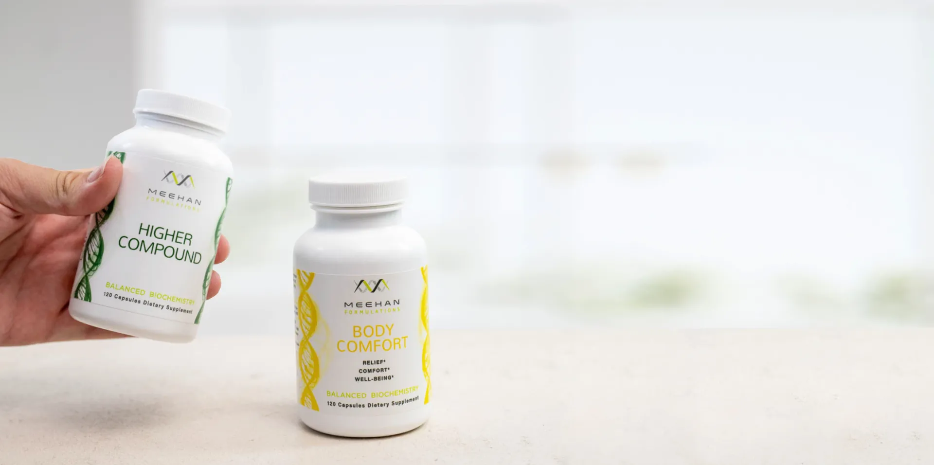 A hand putting a white bottle of Meehan Supplement on top of table