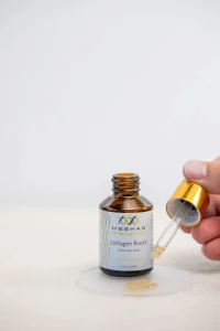 close up of serum bottle and dropper with a hand squeezing the dropper